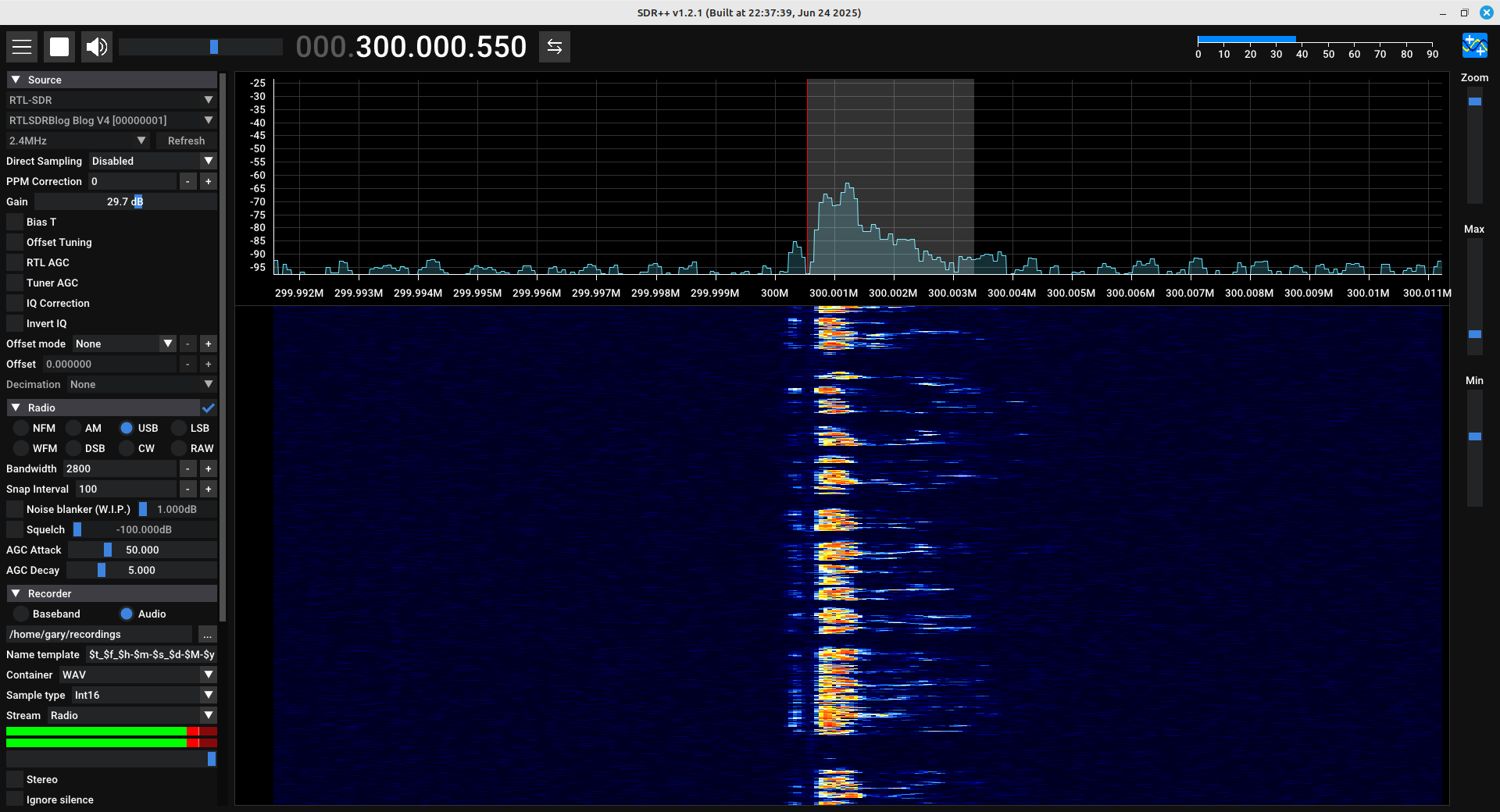 Screenshot of a software defined radio showing a spectral trace on top and a spectrogram on the bottom. The trace and spectrogram show an upper sideband amplitude modulated signal. Along the left is a column showing various parameters of the SDR, including the gain, the demodulator, and a section for recording the signal.